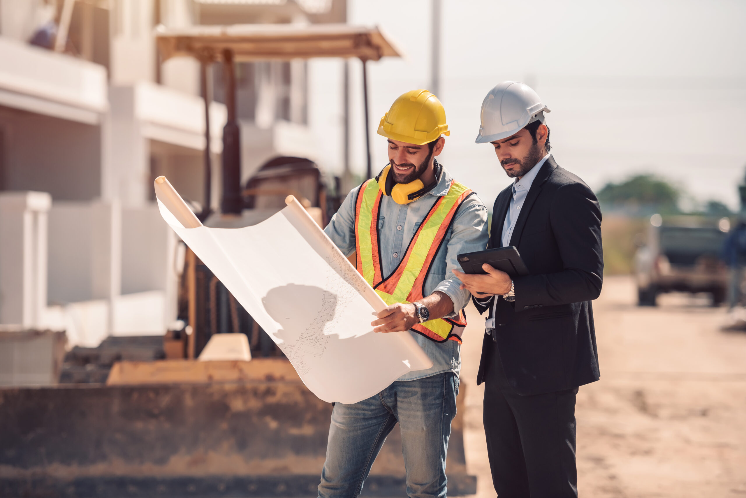 Two civil engineers reviewing blueprints on a modern construction site